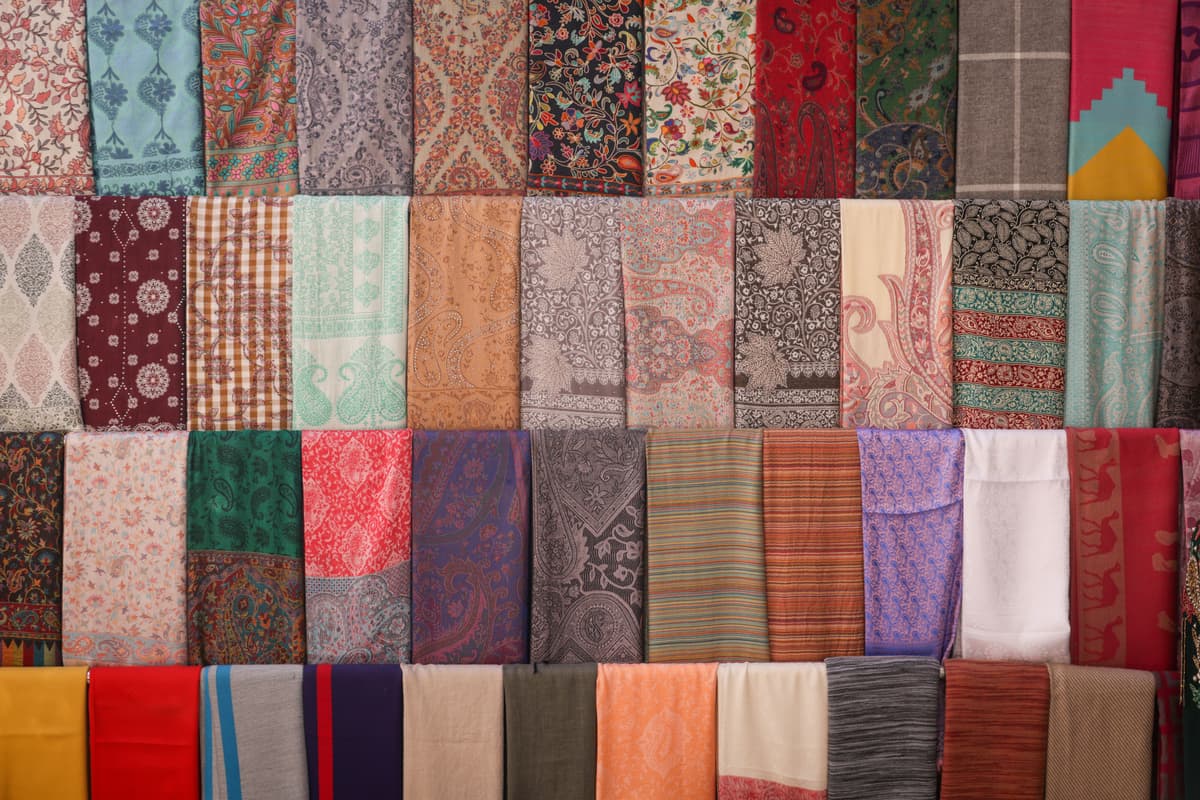 Close-up of a hand browsing through vintage silk scarves